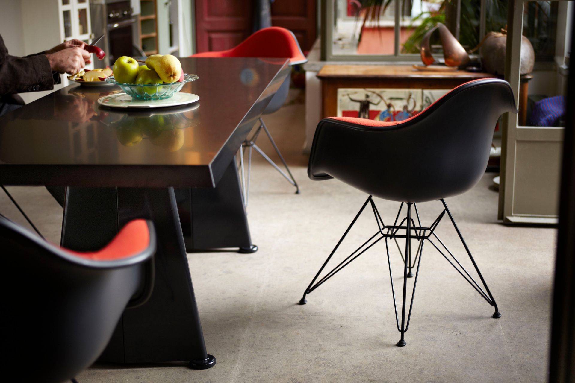 Schwarzer Eames Plastic Arm Chair DAR Stuhl mit rotem Sitzpolster von Vitra im Esszimmer.