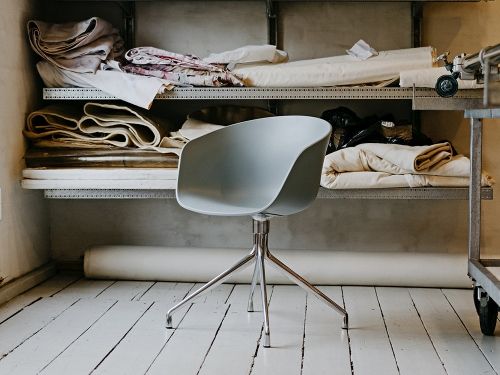 Grauer About A Chair AAC 20 Stuhl von Hay mit Drehgestell vor Regalen.