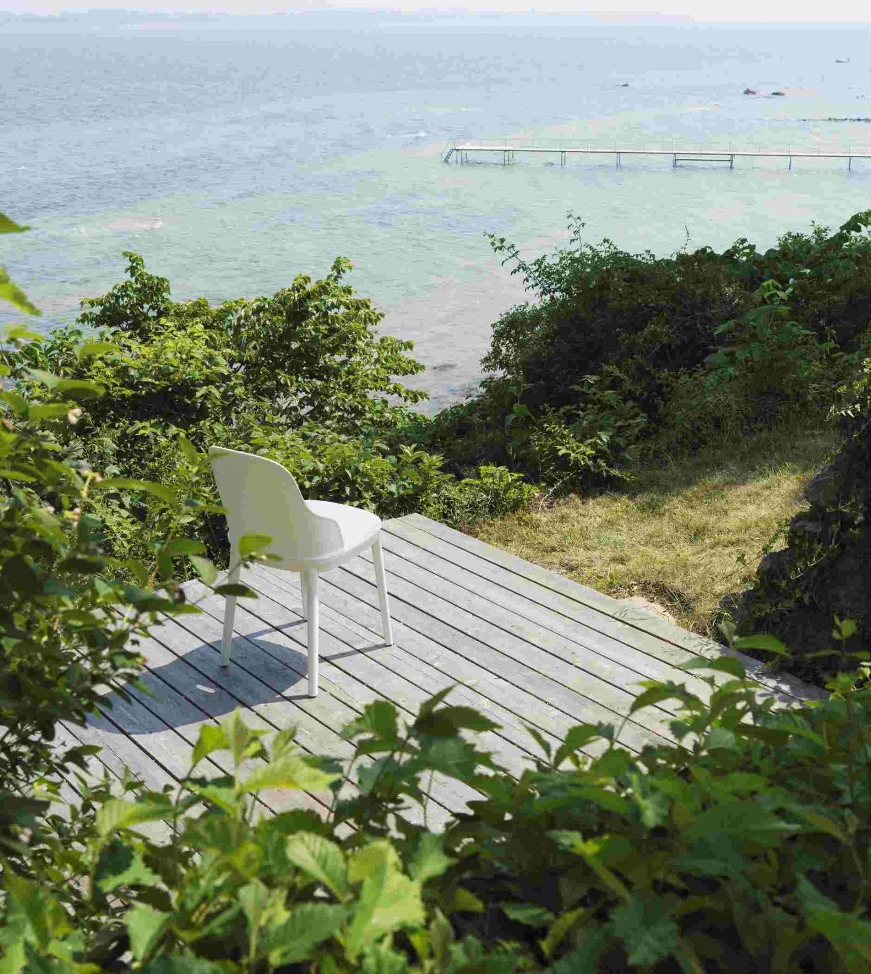 Weißer Allez Chair Stuhl von Normann Copenhagen auf Holzterrasse mit Meerblick, minimalistisches Design und skandinavische Möbel.
