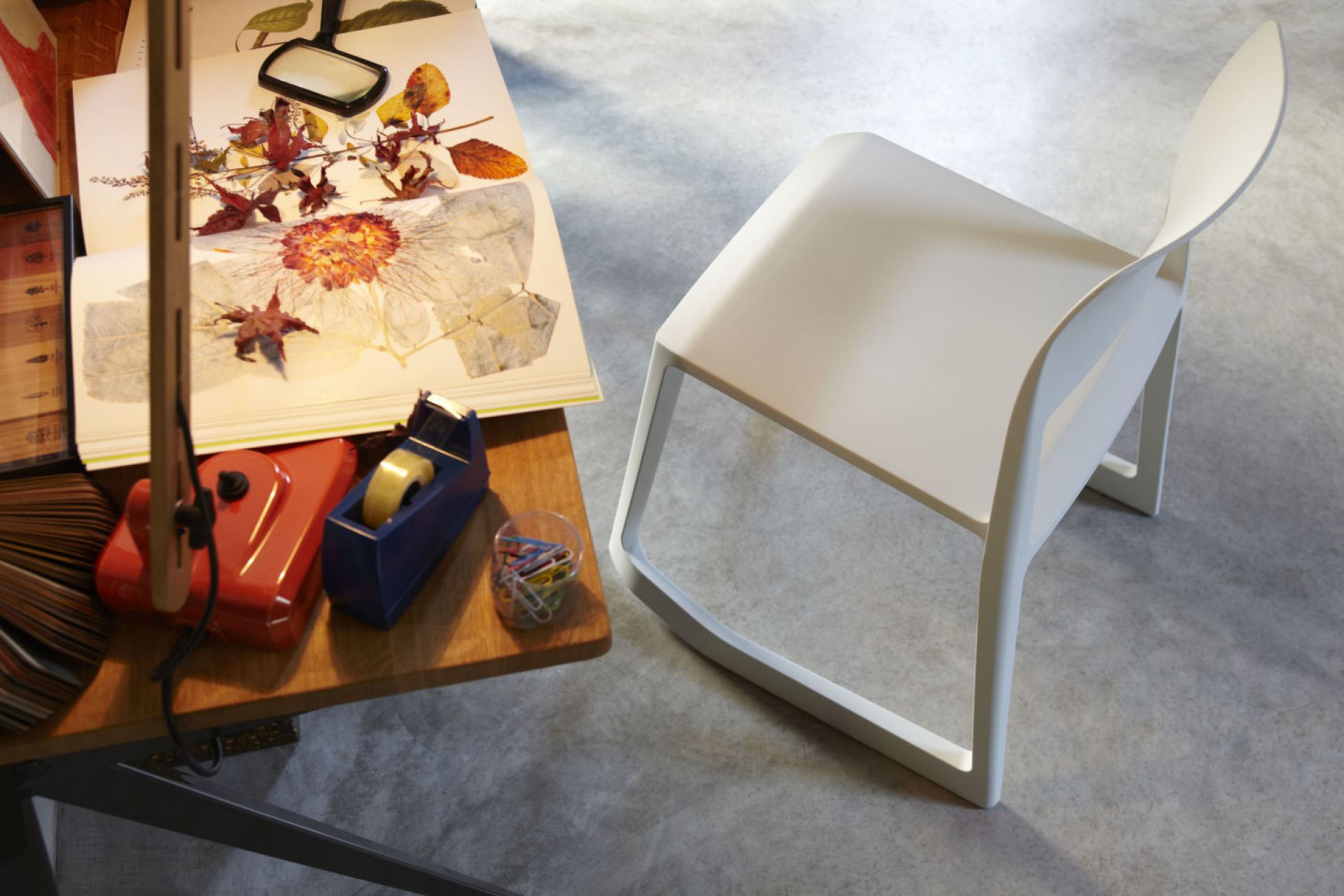 Weißer Tip Ton RE Stuhl von Vitra aus Kunststoff neben Schreibtisch mit Arbeitsmaterialien.