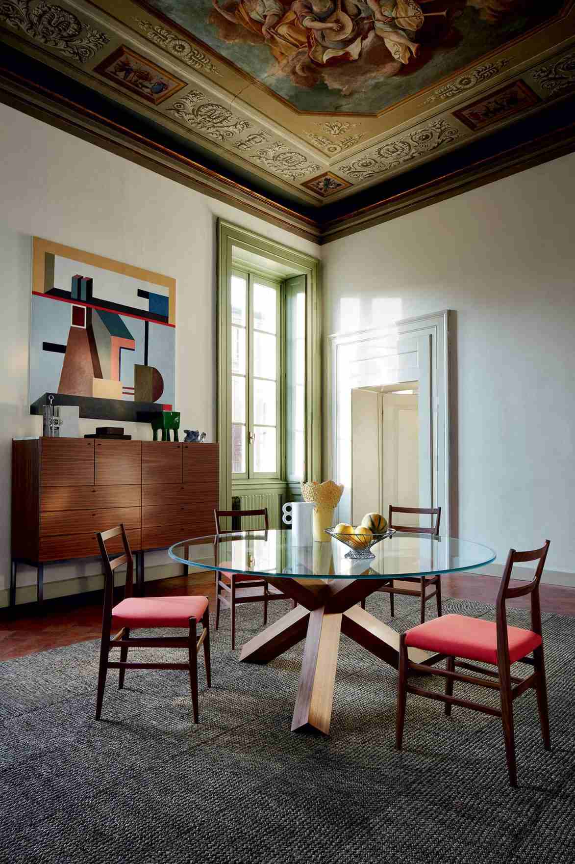 Runder Cassina Esstisch "La Rotonda" mit Glasplatte und Holzfuß, umgeben von Stühlen.