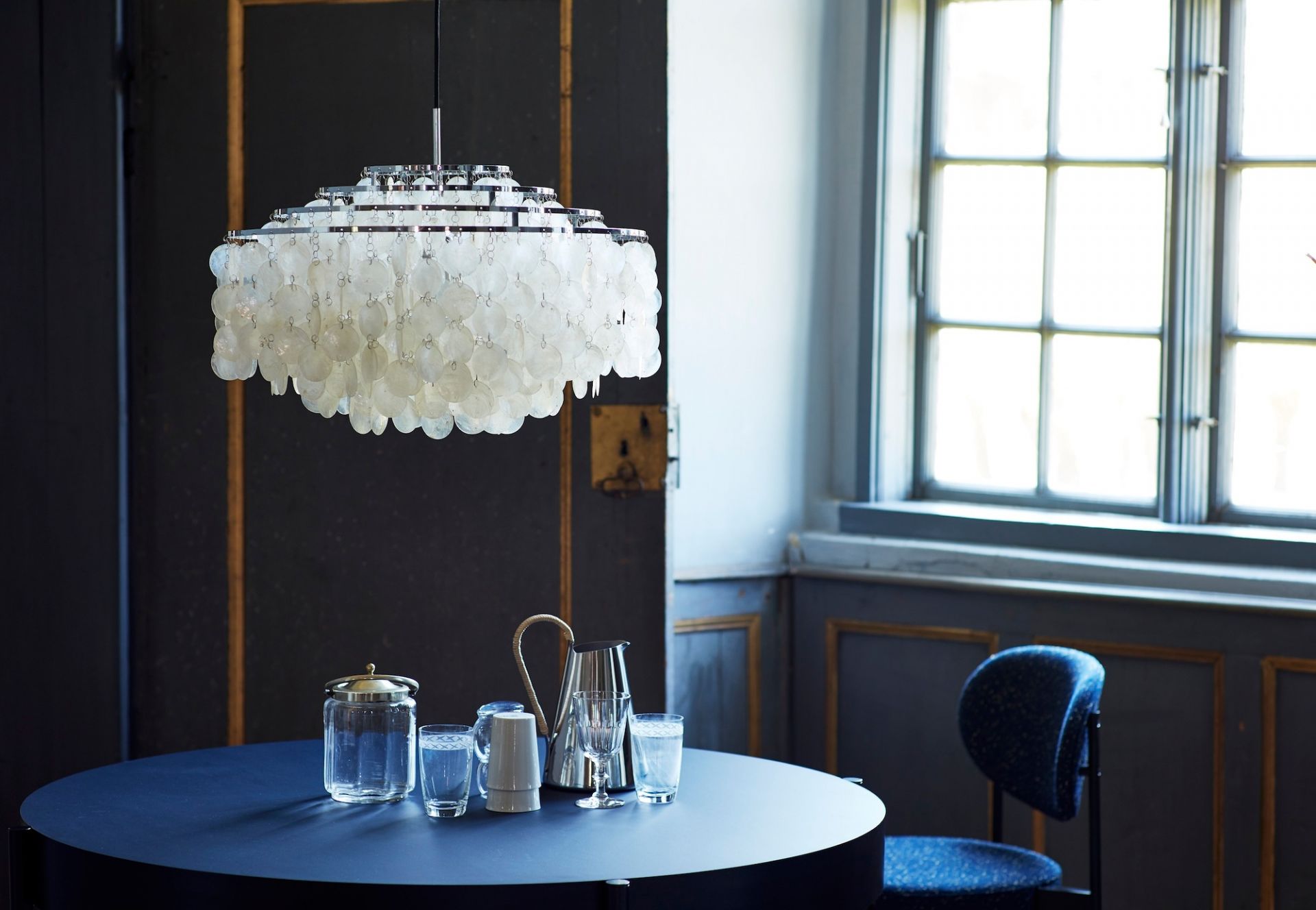 Verpan FUN Pendelleuchte mit Muscheln über blauem Tisch in einem eleganten Interieur.