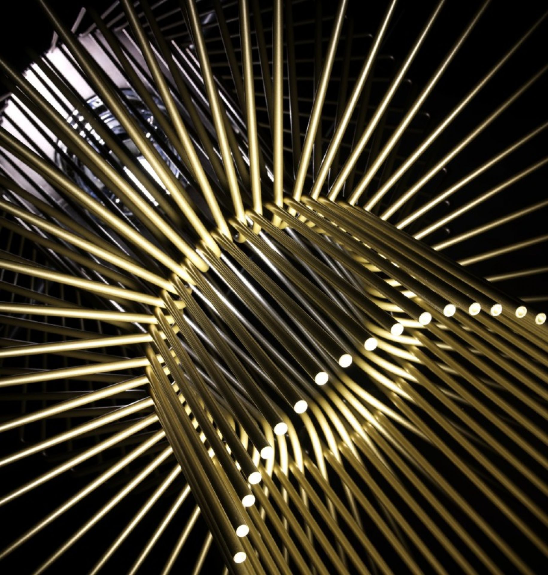 Detailaufnahme der modernen Allegretto Assai Pendelleuchte von Foscarini mit goldenen Metallstäben und Lichtpunkten.