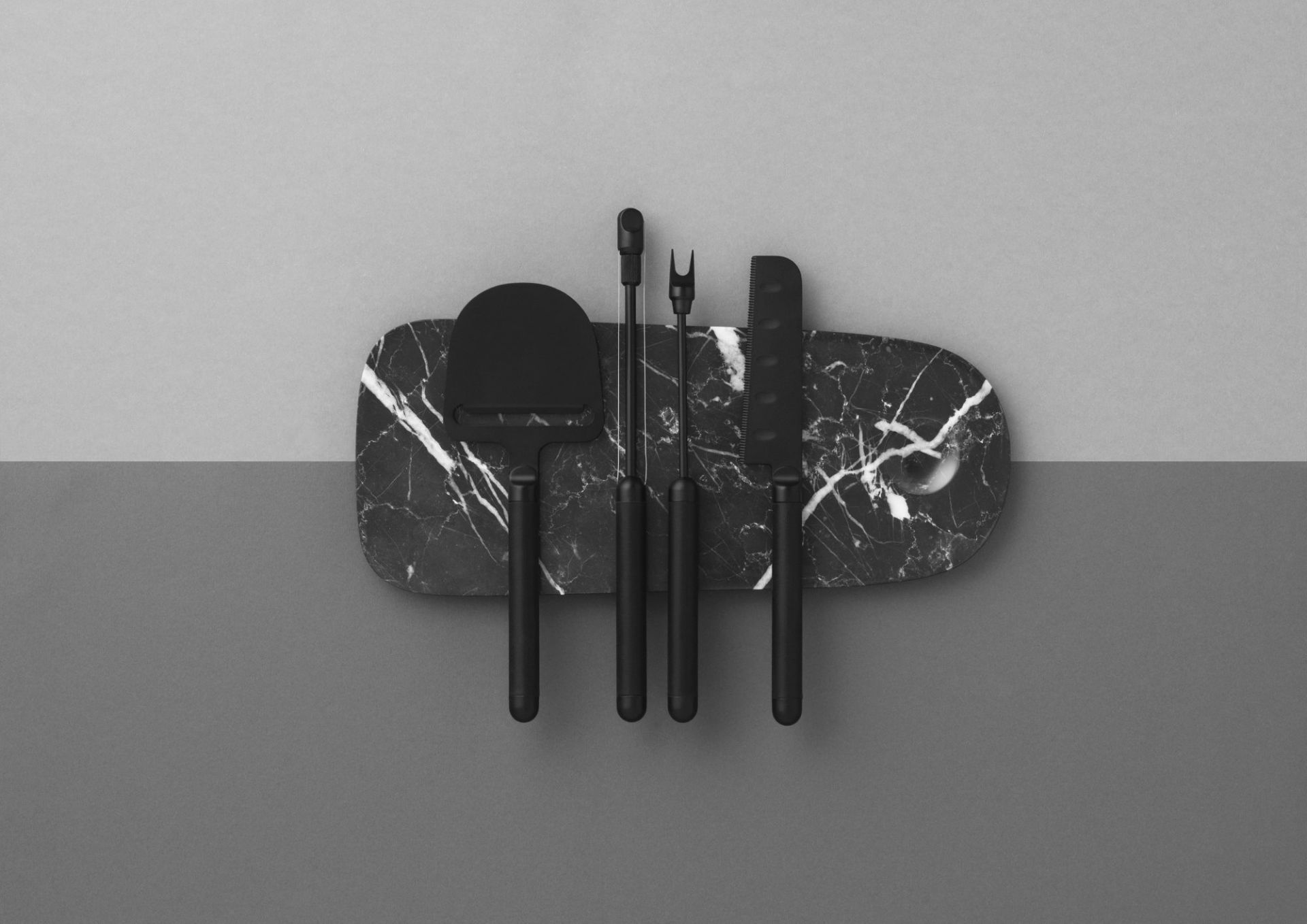 Pebble Board von Normann Copenhagen mit Käsemesser und Käsegabel auf einer Marmor Servierplatte.