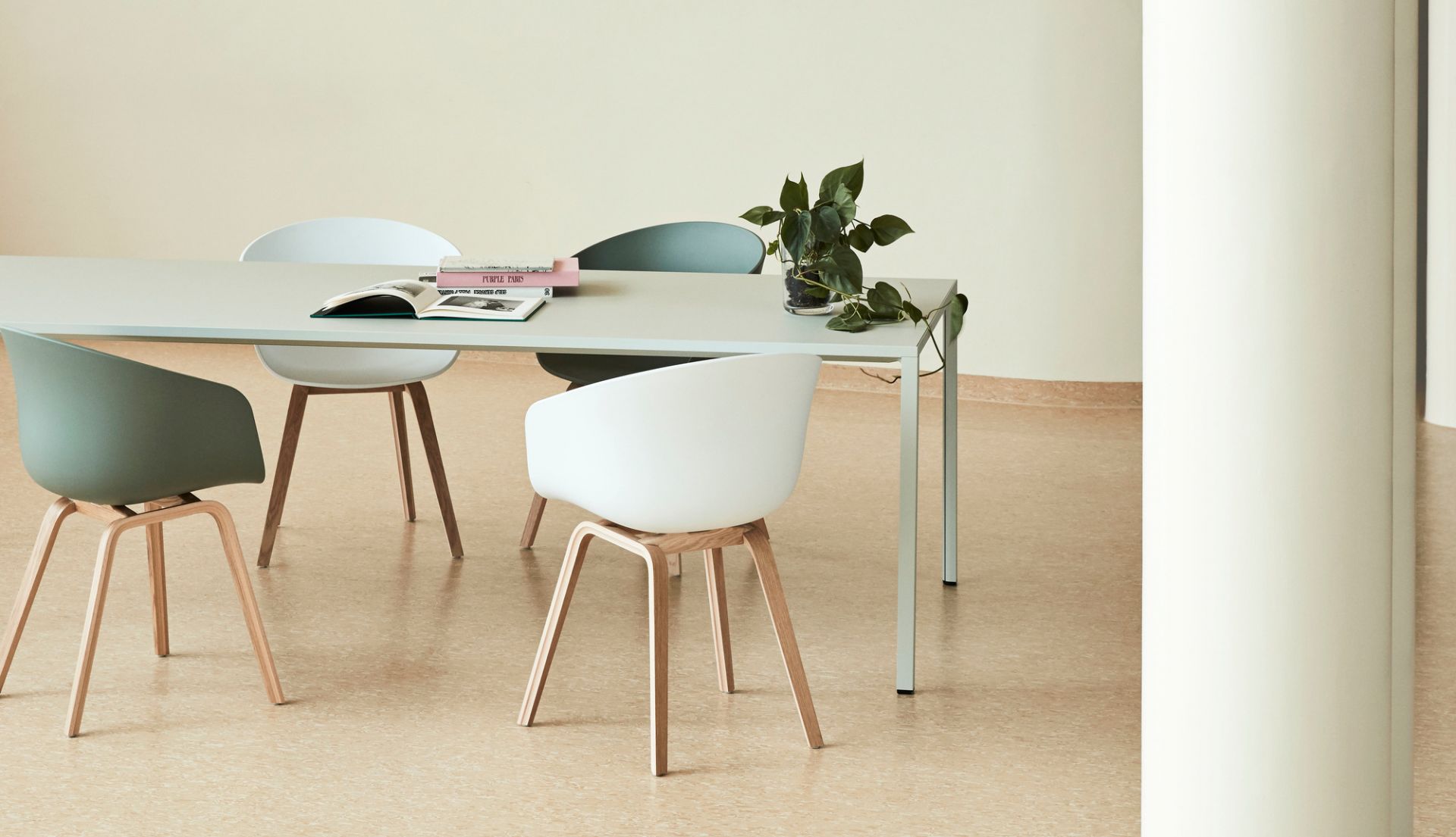 Mehrere About A Chair AAC 22 Stühle von Hay in Weiß und Grün um einen Tisch.