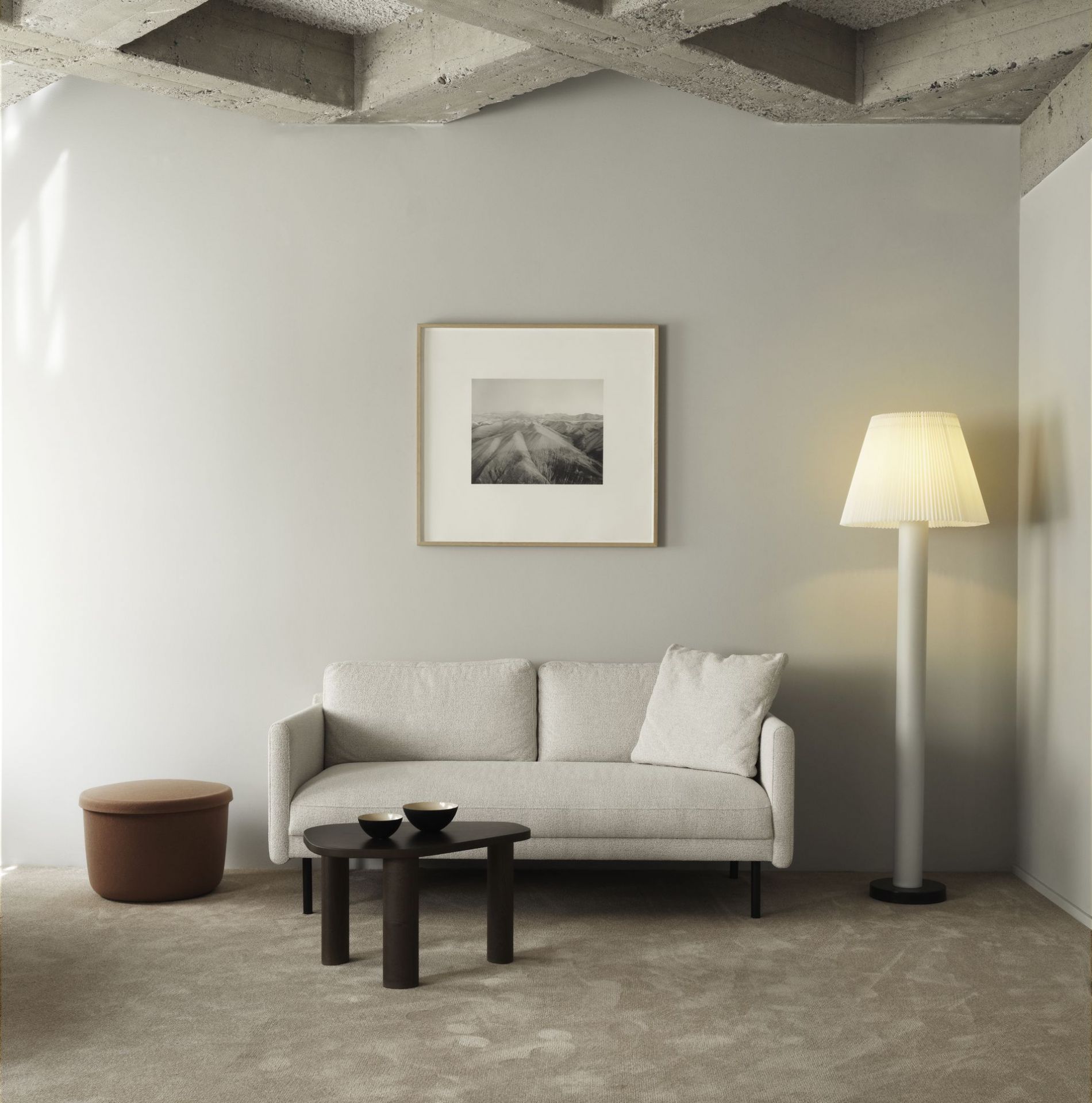 Helles Wohnzimmer mit Normann Copenhagen Rar Sofa 2-Sitzer, Beistelltisch, Stehlampe und Ottomane auf einem Teppich.