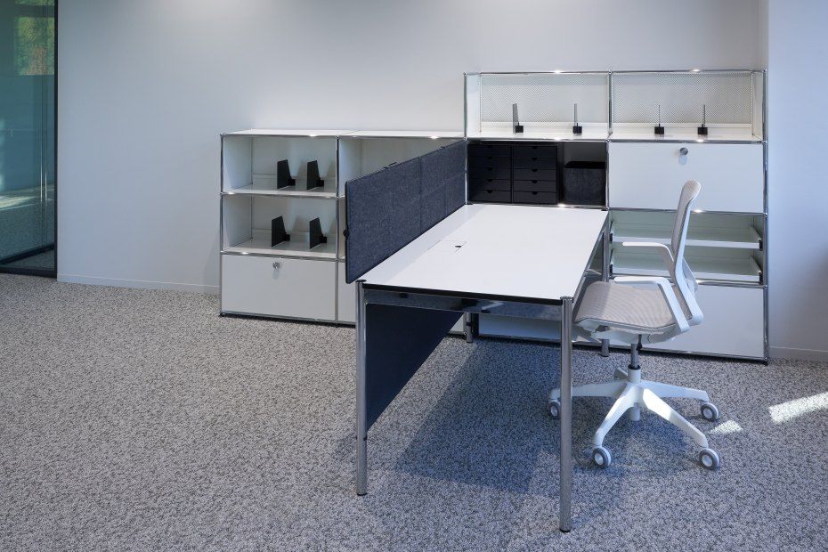 USM Haller Büromöbel: Schreibtisch mit Privacy Panels und Rollcontainer in modernem Büro.