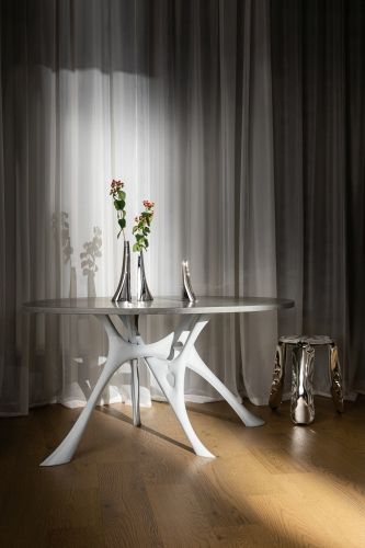 Plopp Hocker Limited Edition aus Metall neben Esstisch mit weißem Gestell und Dekoration.