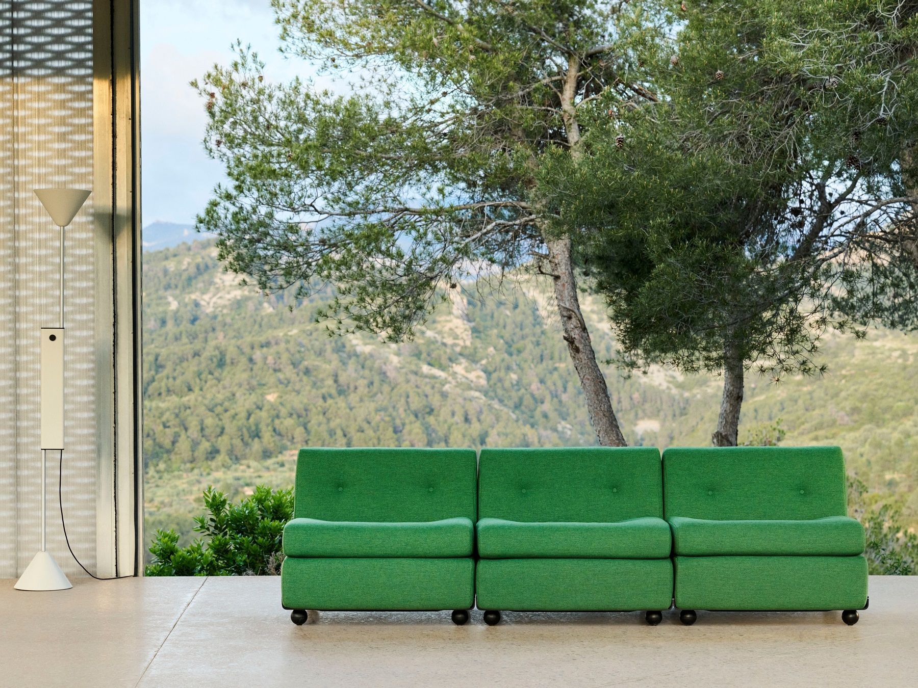 Hay Twist Floor Lamp Stehleuchte in modernem Interieur mit grünem Sofa und Bergpanorama.