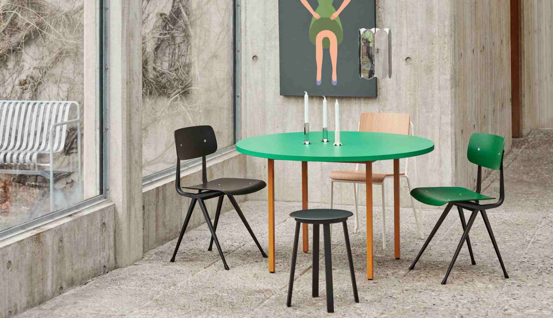Heller Raum mit Hay Two Colour Table Tisch mit grüner Platte und farbigen Stühlen.
