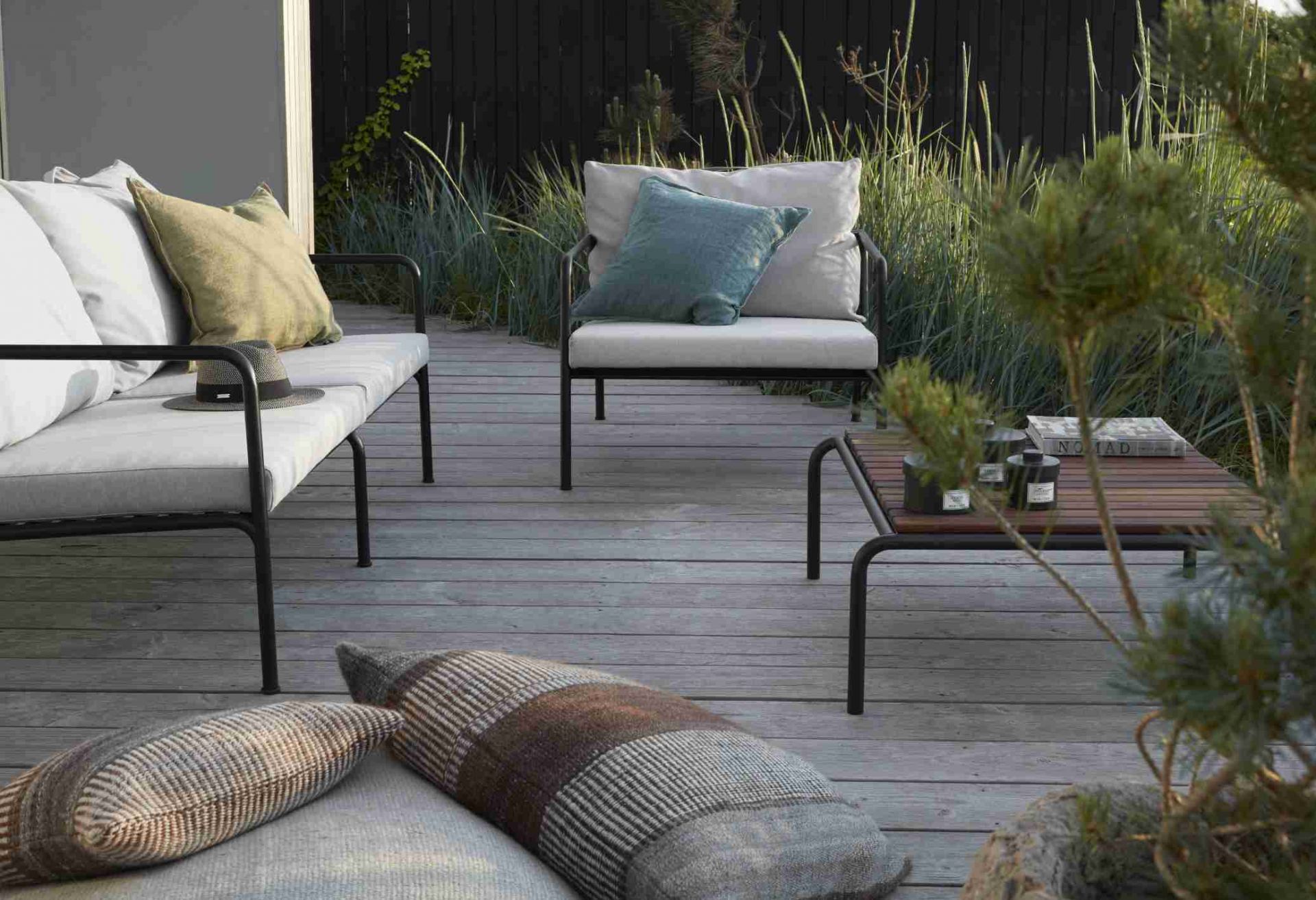 Avon Lounge Table Outdoor Tisch Houe auf Holzterrasse mit Sofa, Sessel und Kissen.
