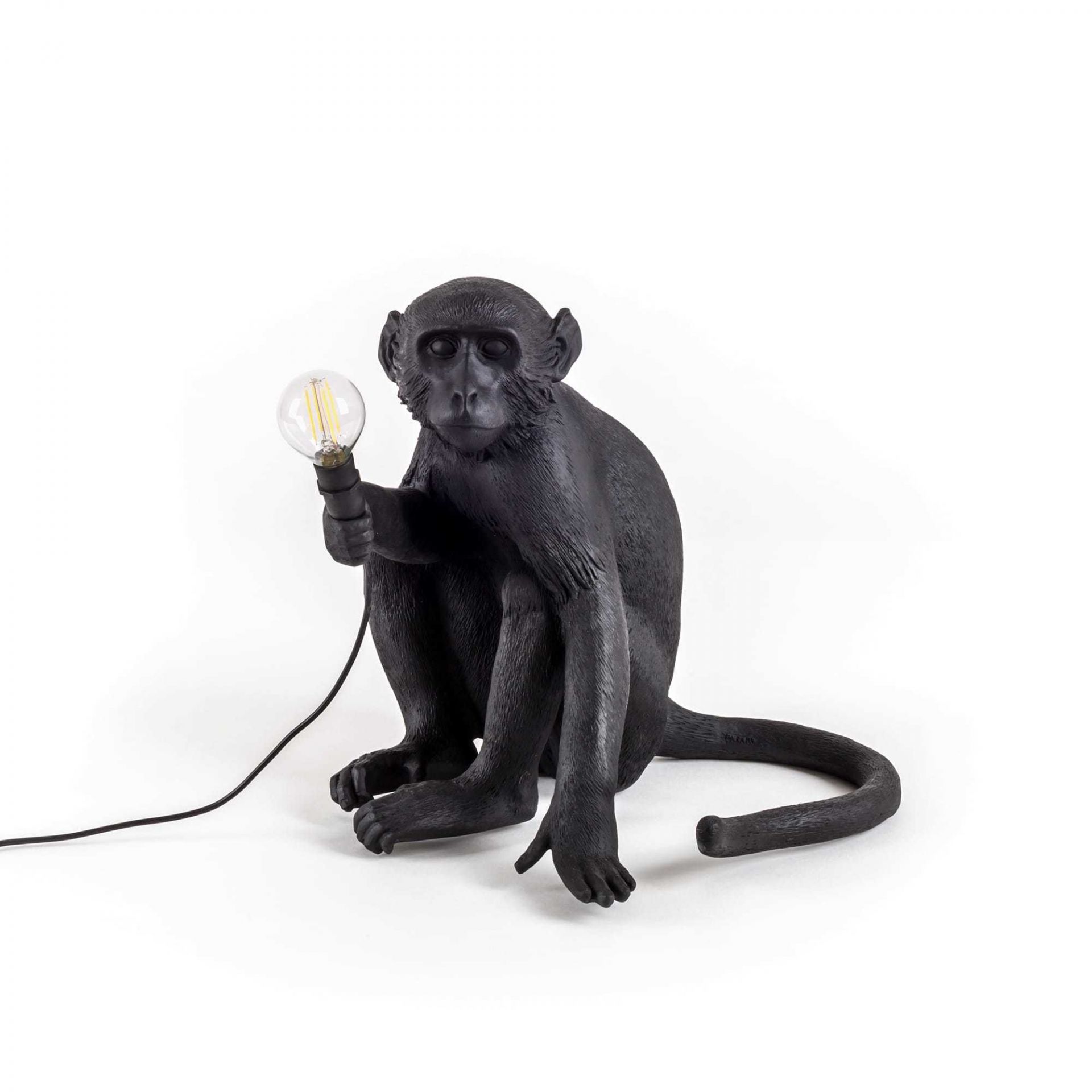 Schwarze Seletti Affenlampe, sitzend, hält eine Glühbirne. Dekorative Tischleuchte für Innen und Außen.