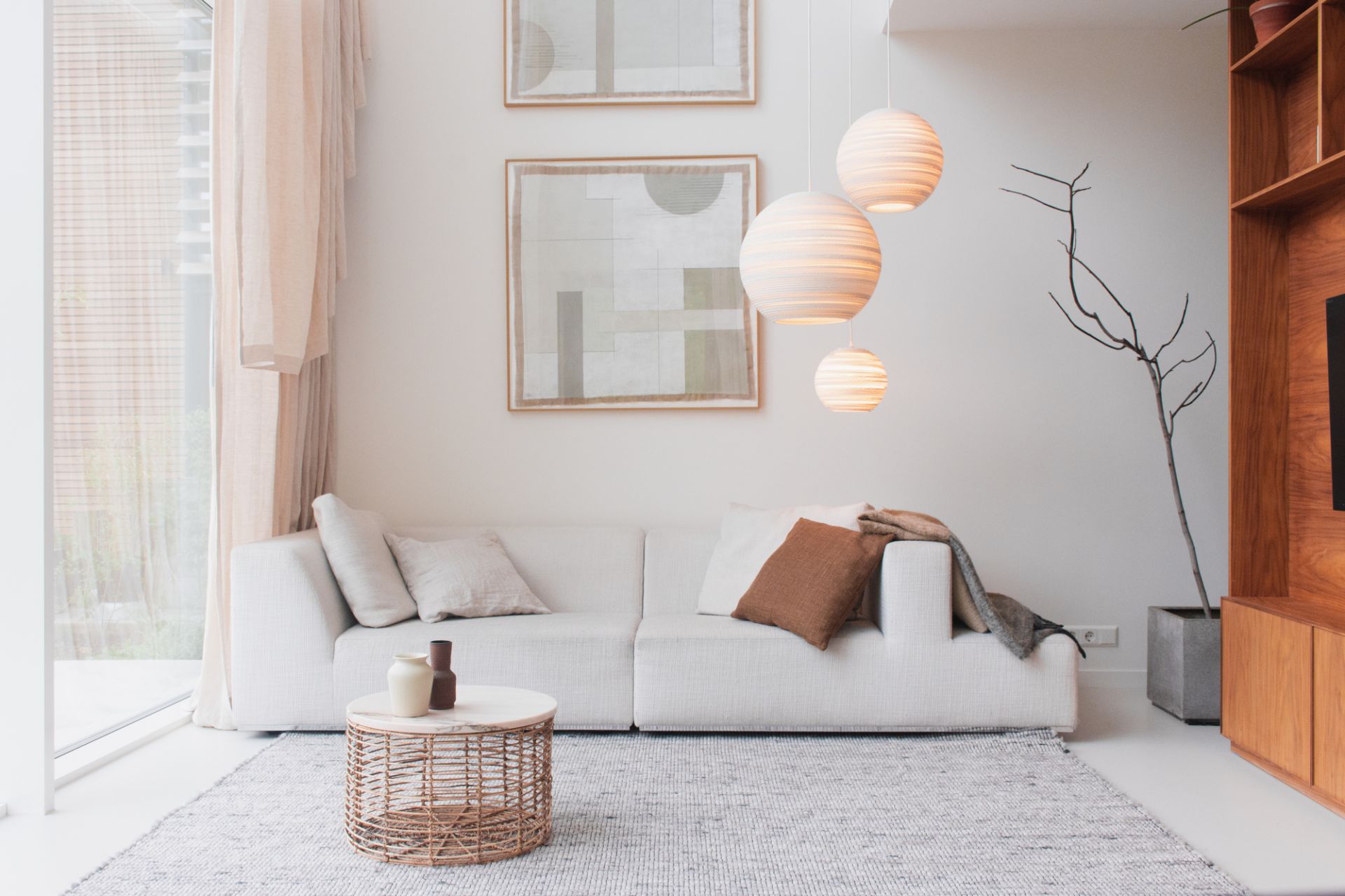 Helle Wohnzimmer-Szene mit Graypants Scraplights Moon Hängeleuchten über einem weißen Sofa.