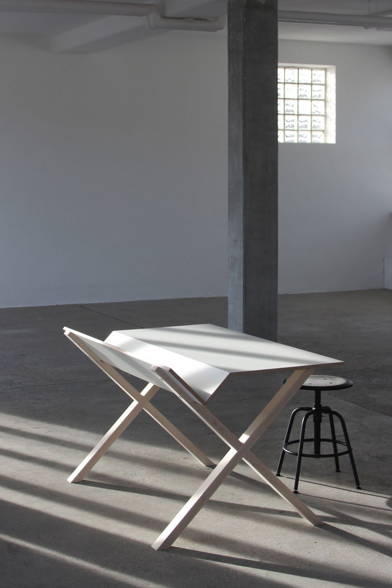 Nils Holger Moormann Kant Schreibtisch aus hellem Holz und weißer Tischplatte in minimalistischem Raum.
