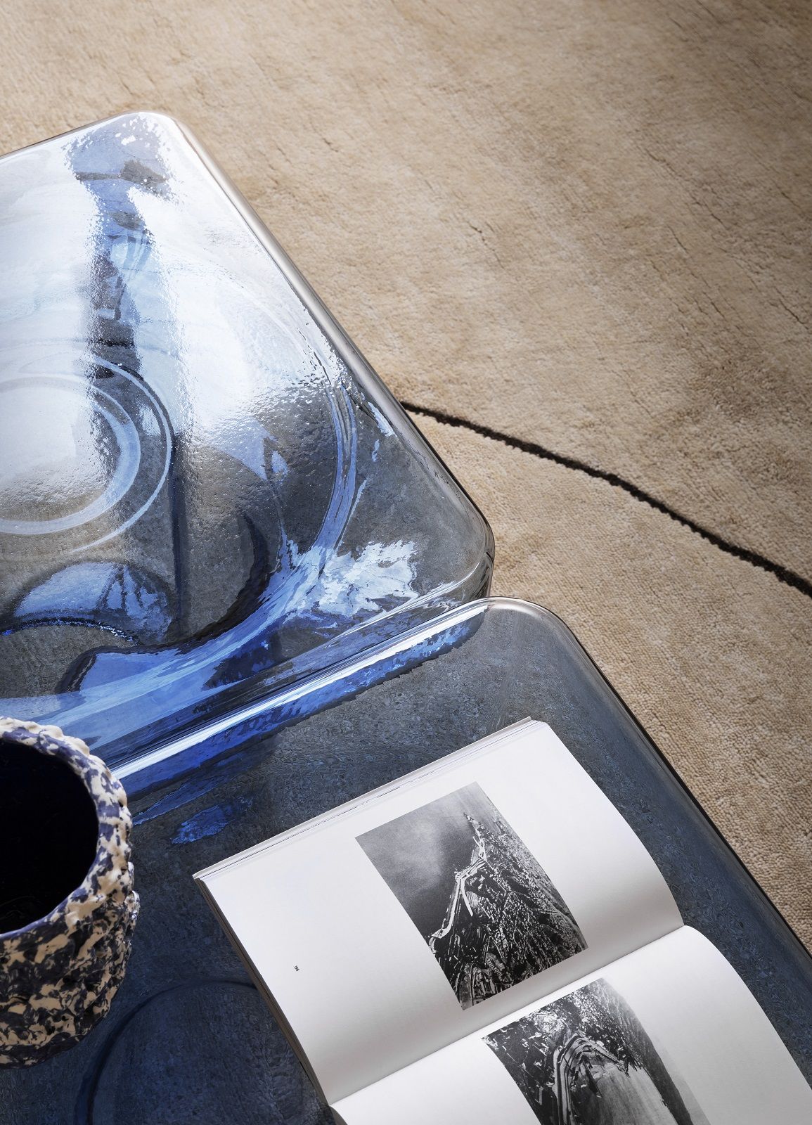 Detailaufnahme: Blauer Soda Couchtisch von Miniforms mit Buch und Dekoration auf beigem Teppich.