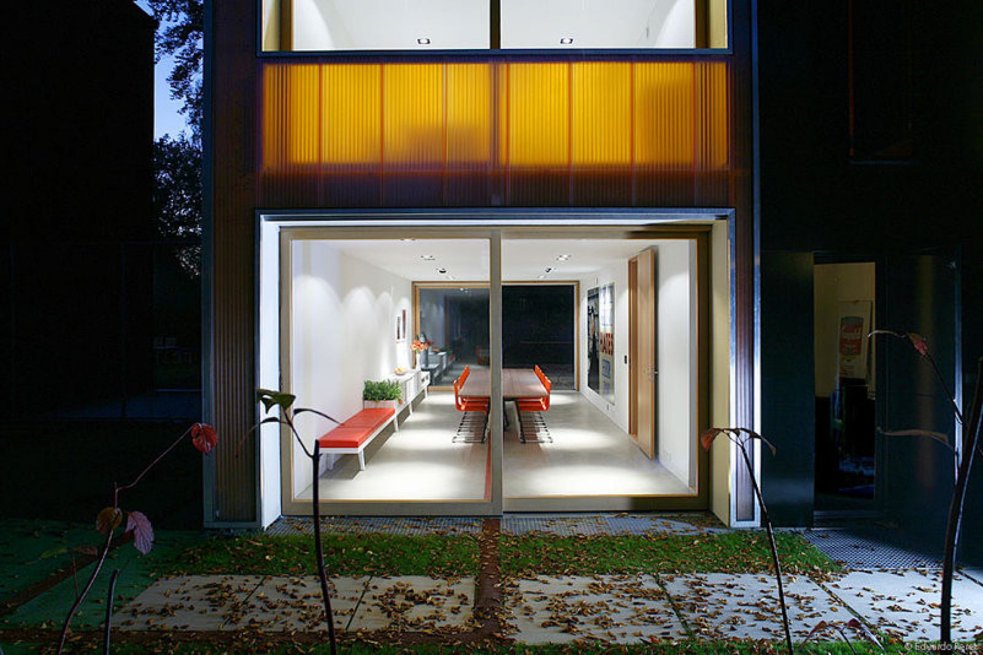 Innenaufnahme eines modernen Hauses mit Vitra .05 Stühlen in Orange um einen Holztisch gruppiert.
