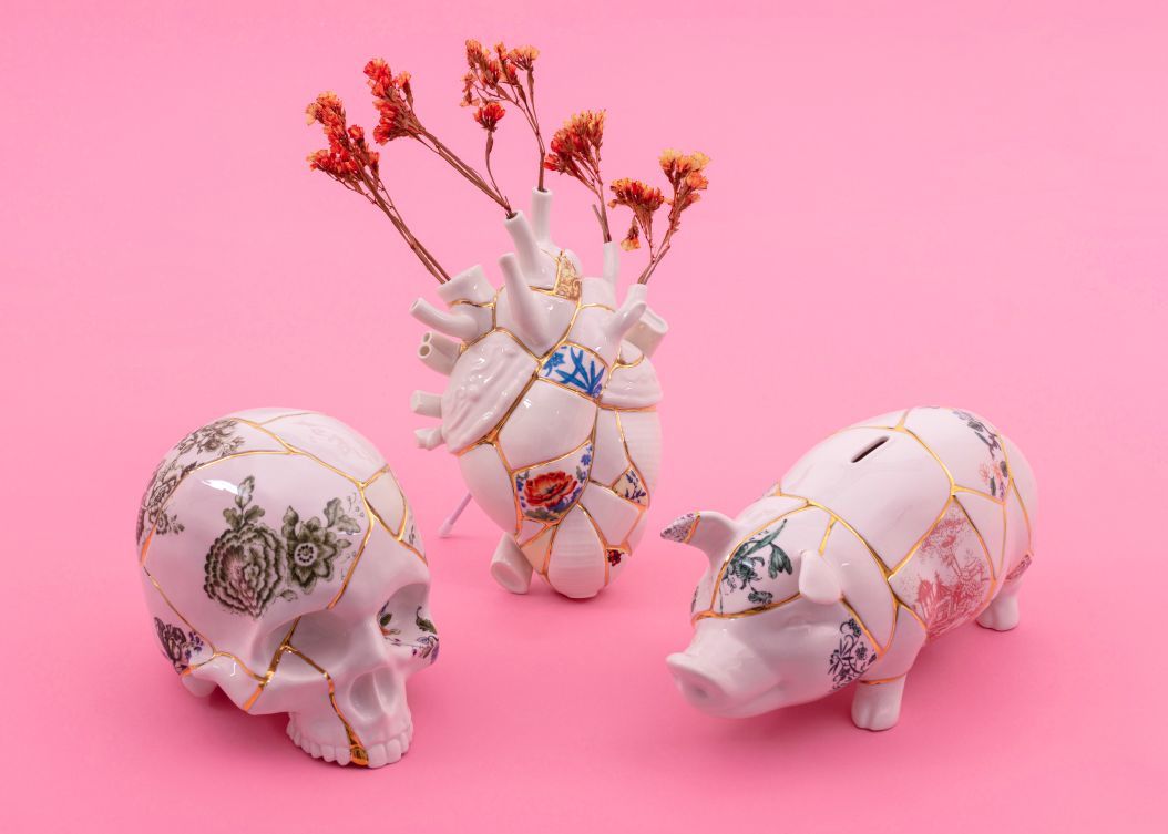 Kintsugi Spardosen Set: Totenkopf, Herz-Vase mit Trockenblumen und Schwein, Porzellan mit Goldreparatur auf Pink.