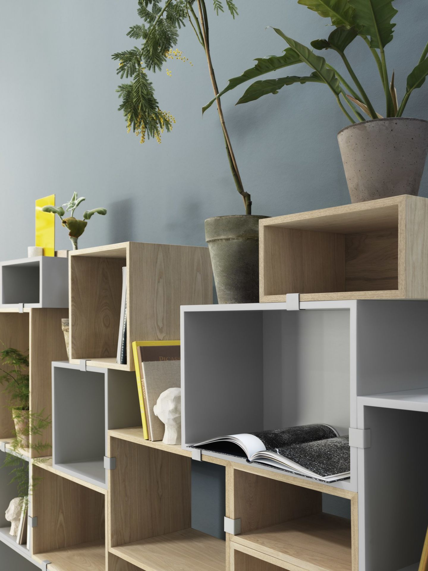 Muuto Stacked Storage System 2.0 Regalsystem aus grauen und hellbraunen Modulen mit Pflanzen und Deko.