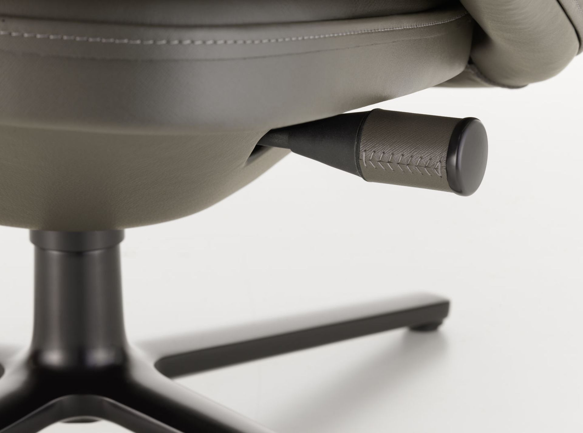 Detailaufnahme des Vitra Grand Relax Sessels: Verstellhebel und Drehfuß in elegantem Grau und Schwarz.