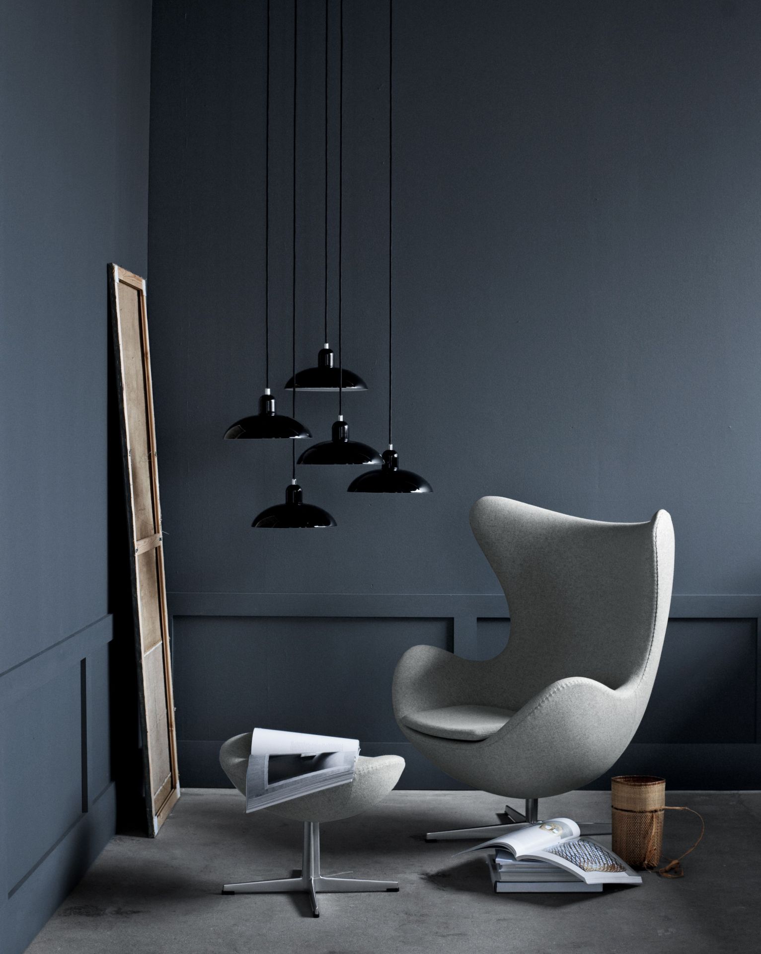 Grauer Egg Chair Sessel mit Hocker von Fritz Hansen und schwarzen Pendelleuchten im modernen Wohnzimmer.