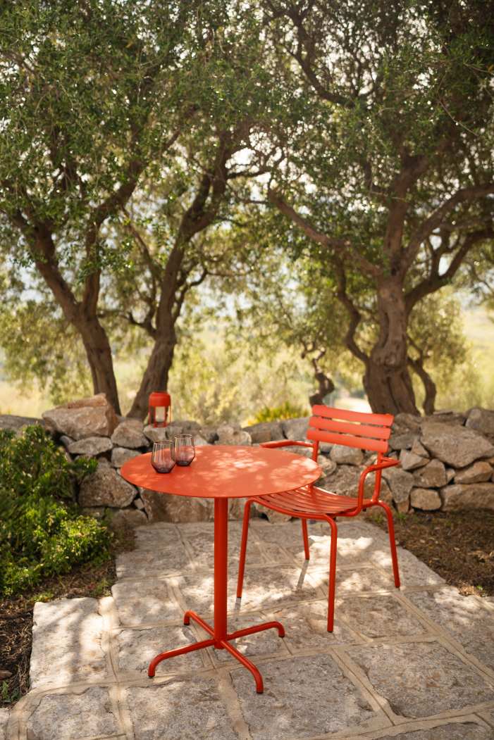 Alua Armrest Dining Chair von Houe, roter Outdoor Armlehnstuhl mit Tisch auf Steinterrasse.