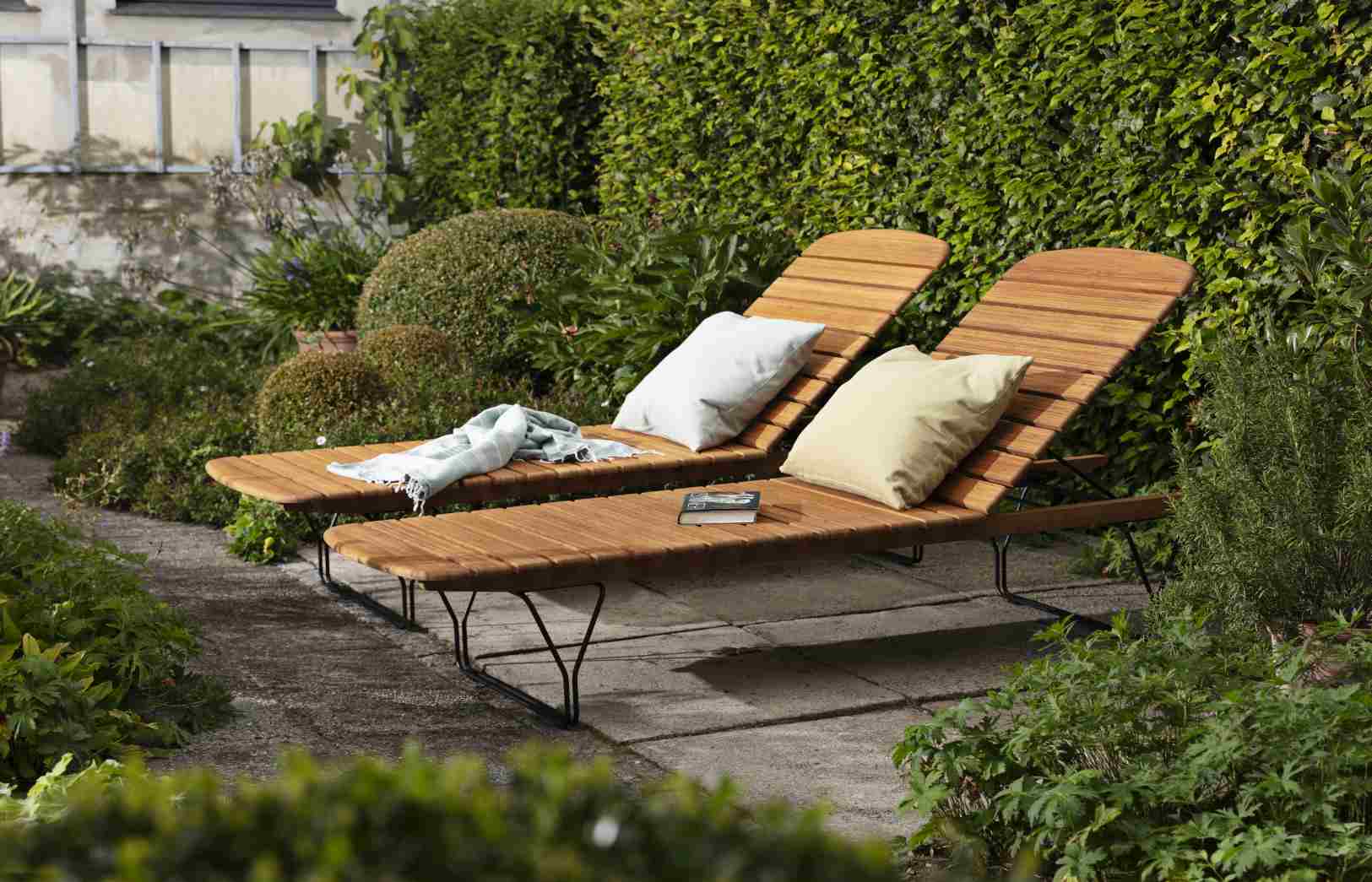 Zwei Molo Sonnenliegen aus Holz im Garten mit Kissen und Decke. Outdoor Möbel.