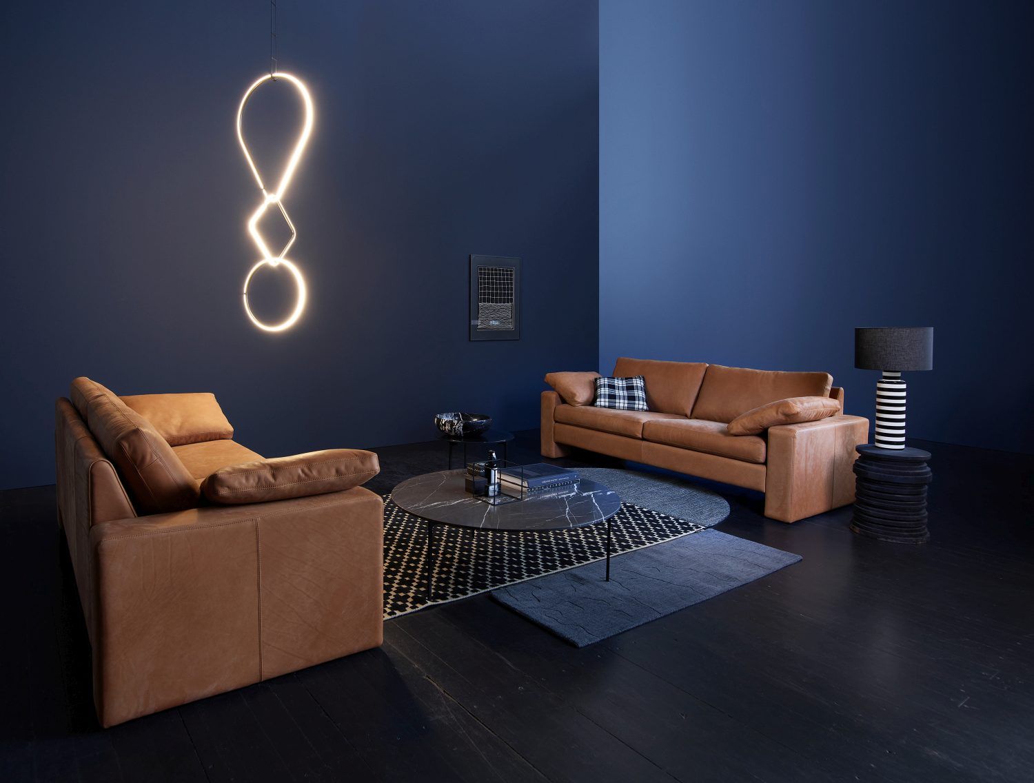 Helles Conseta Ledersofa und Sessel in modernem Wohnzimmer mit blauen Wänden und Designelementen.
