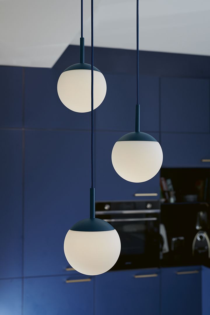 Mooon Pendelleuchte von Fermob: Drei runde, weiße Lampenschirme mit blauem Gestell hängen von der Decke.