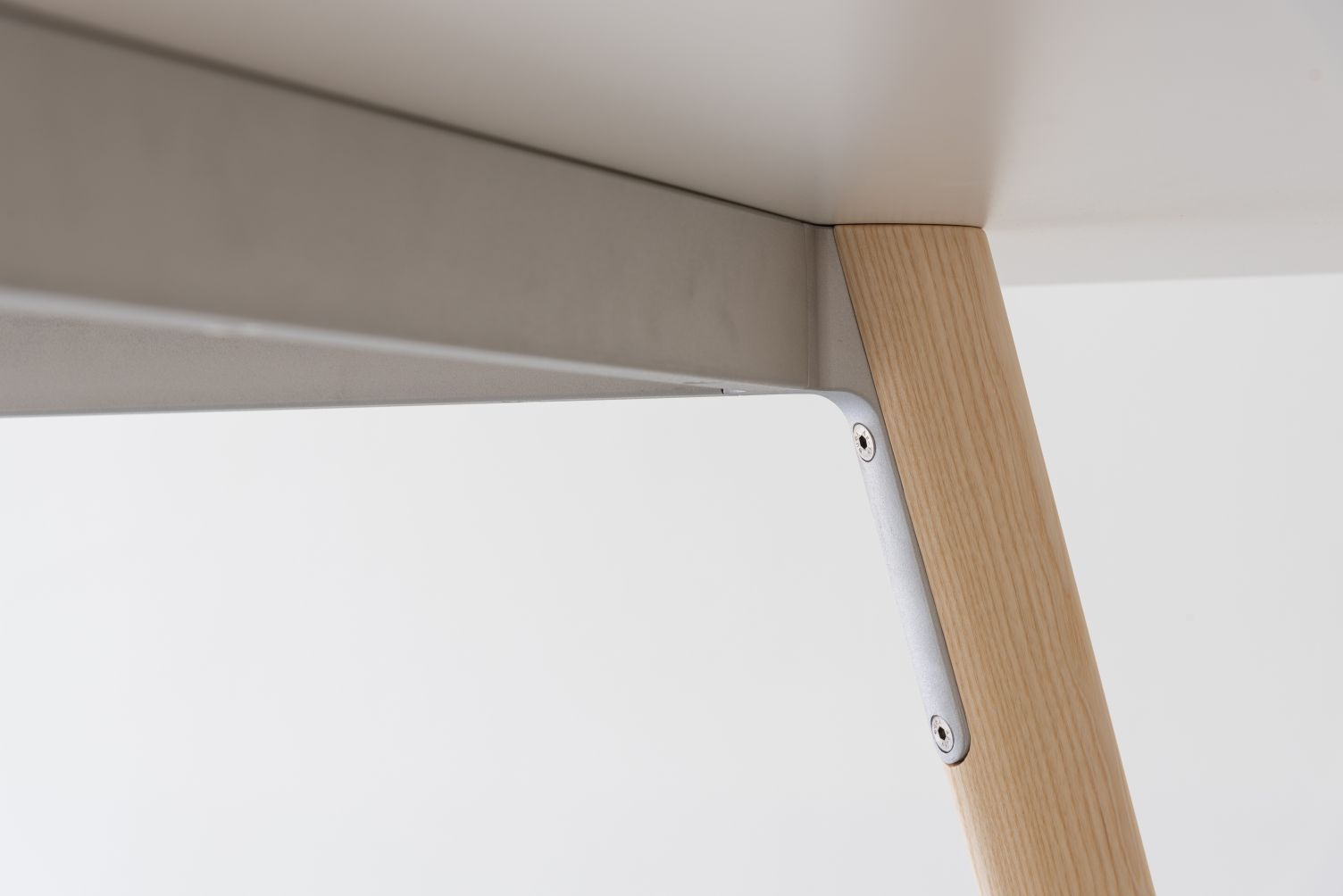 Detailaufnahme vom Pilo Tisch von Magis: Holzbein, Metallrahmen und Tischplatte in neutralen Farben.