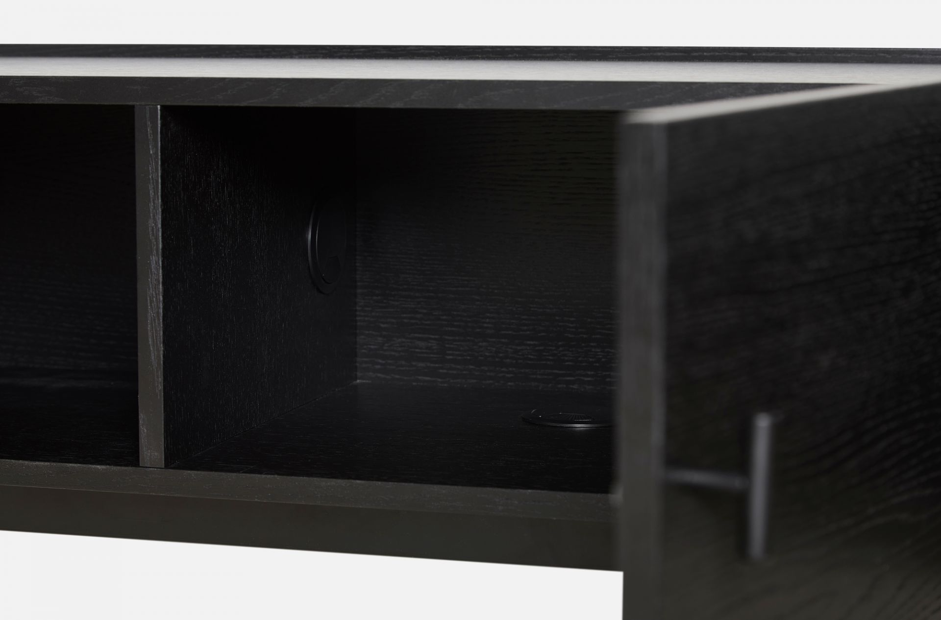 Detailaufnahme des Woud Array Low Sideboards (150cm) in Schwarz, mit offener Tür und Kabeldurchlass für TV-Möbel.