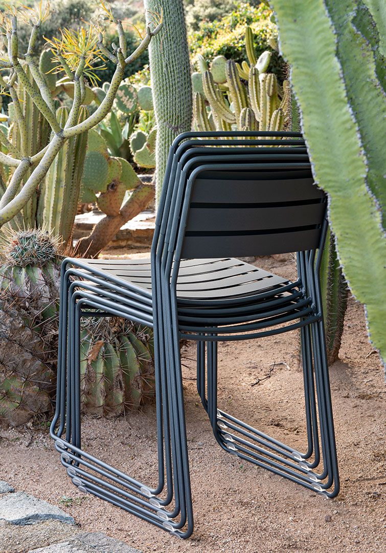 Stapel grauer Fermob Surprising Chair Outdoor Stühle vor Kakteen im Garten. Gartenmöbel aus Metall.