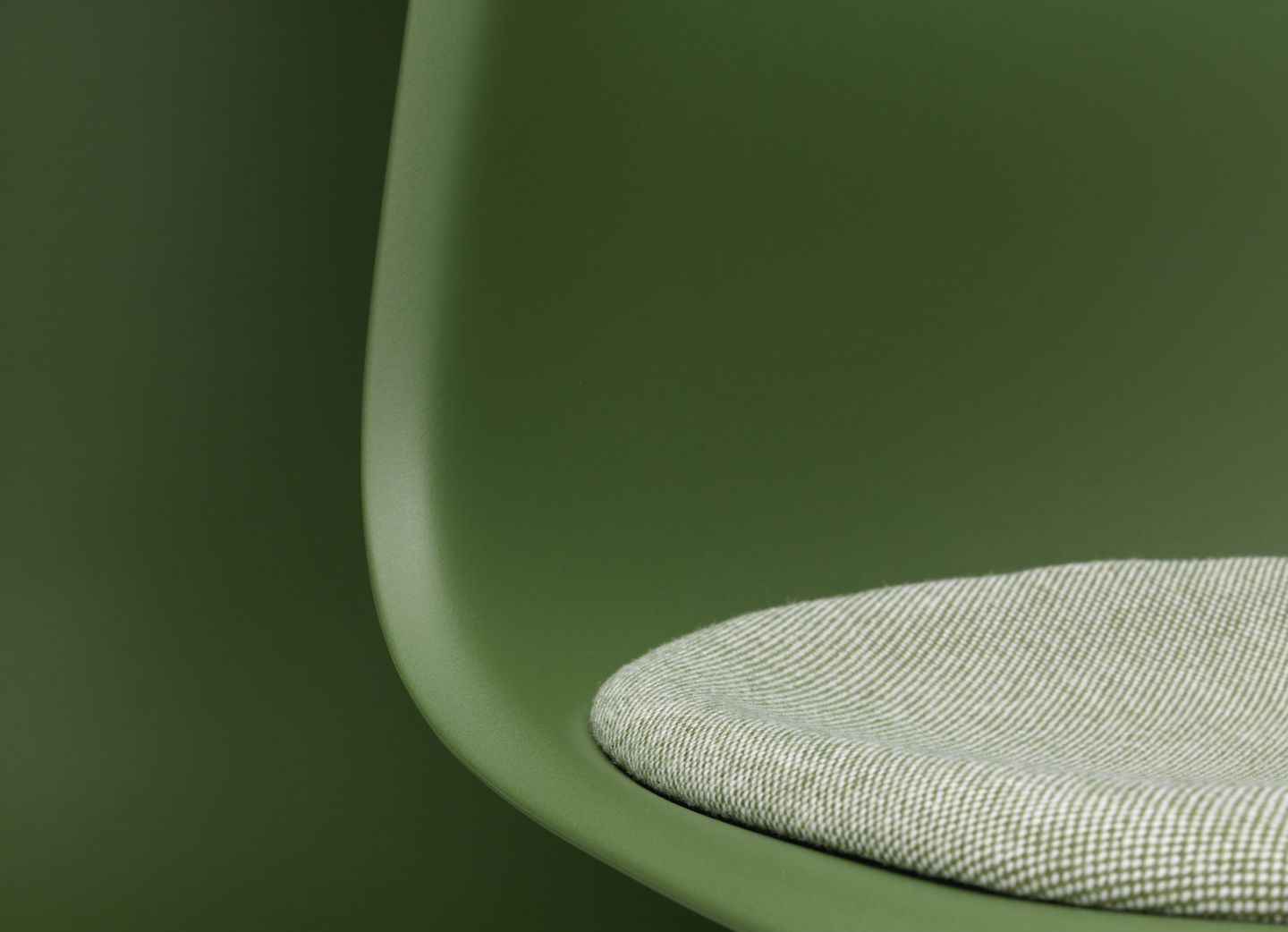 Detailaufnahme: Grüner Eames DSR Stuhl von Vitra mit Sitzpolster für bequemes Sitzen im Wohnbereich.