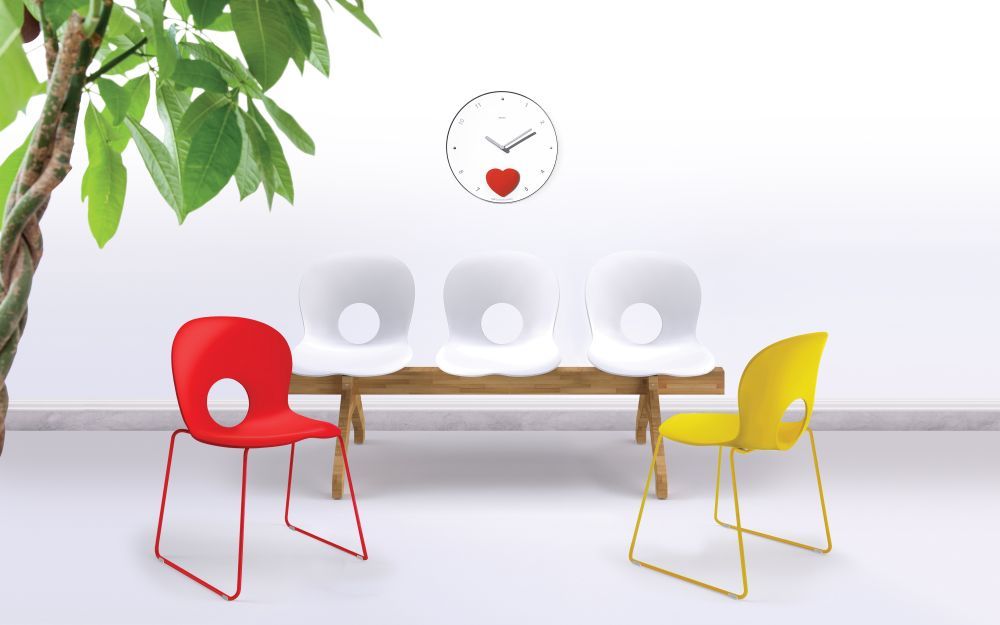 Helle Wartezimmer-Szene mit Rexite Appuntamento Wanduhr und bunten Design-Stühlen.