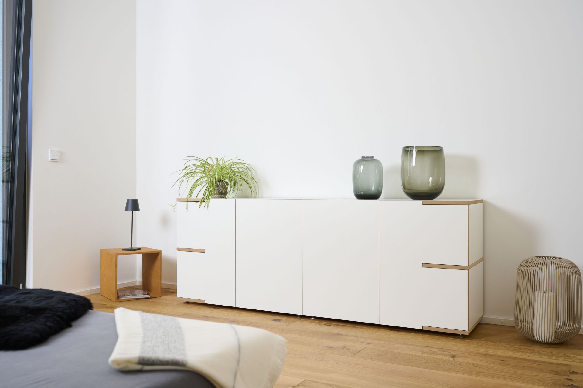 Helles Wohnzimmer mit Tojo Sideboard, weißem Lowboard, Dekoration und Holzboden für moderne Einrichtung.