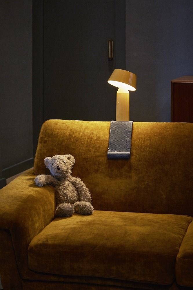 Marset Bicoca Tischleuchte in Gelb auf Sofa mit Teddybär, stimmungsvolle Akkuleuchte.