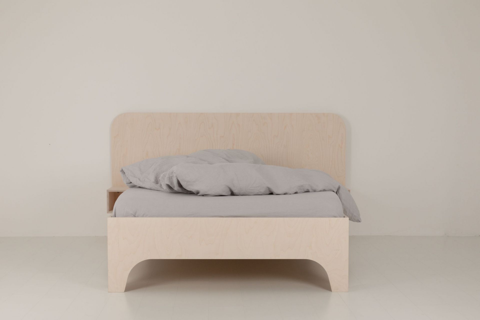 VALENTINA Bett aus hellem Holz mit grauer Bettwäsche und Nachttischablage für ein minimalistisches Schlafzimmer.