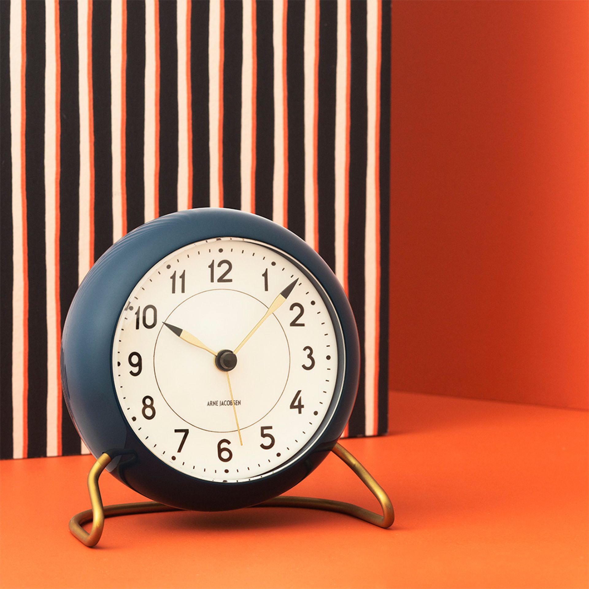 Petrolfarbene Arne Jacobsen Tischuhr "Station" von Rosendahl Timepieces mit weißem Zifferblatt und goldenem Fuß.