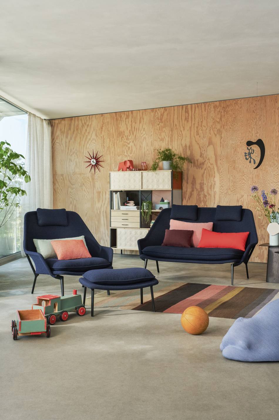 Blauer Vitra Slow Chair Sessel mit Ottoman und Sofa in modernem Wohnzimmer.