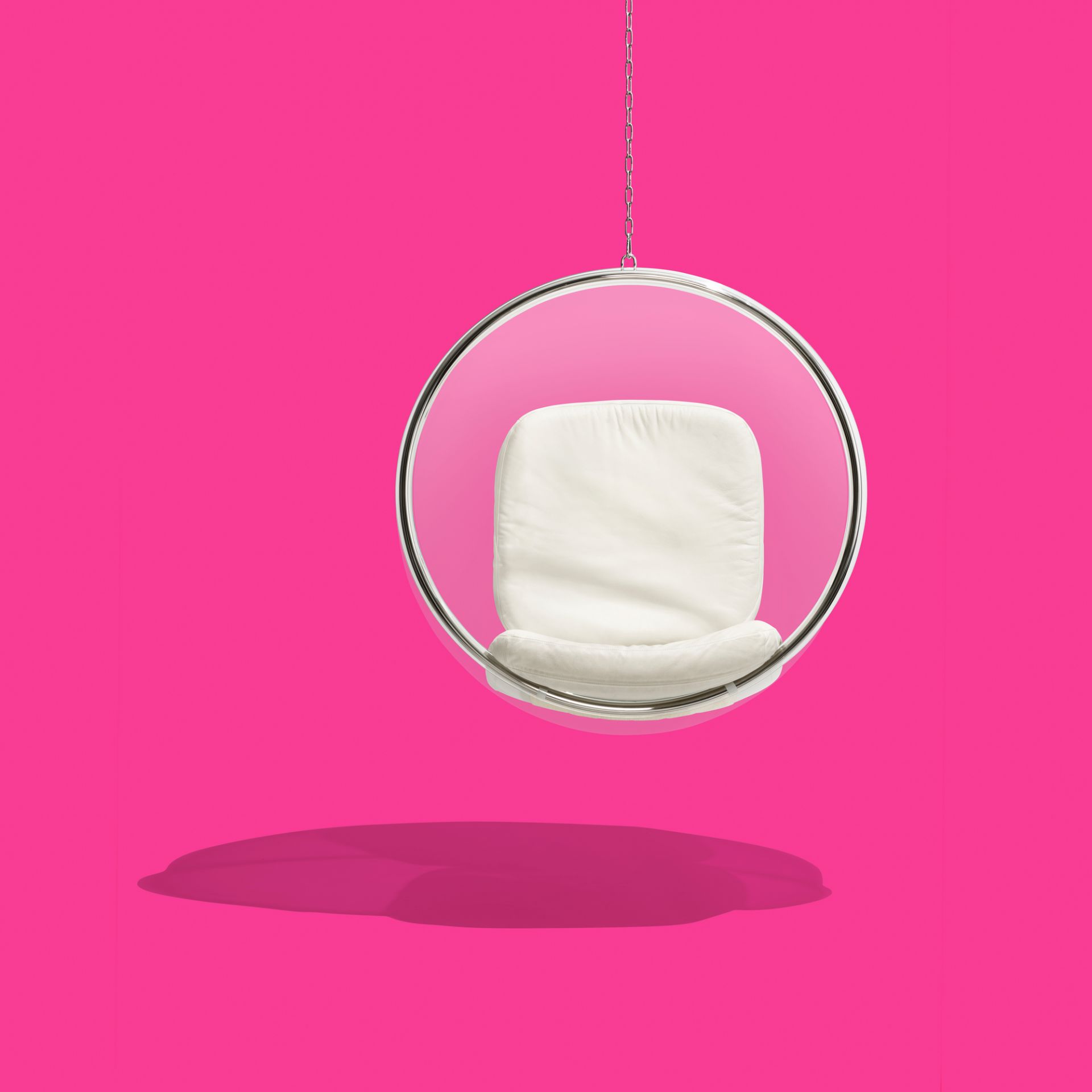 Bubble Chair Hängesessel von Eero Aarnio Originals mit weißem Kissen vor pinkfarbenem Hintergrund.
