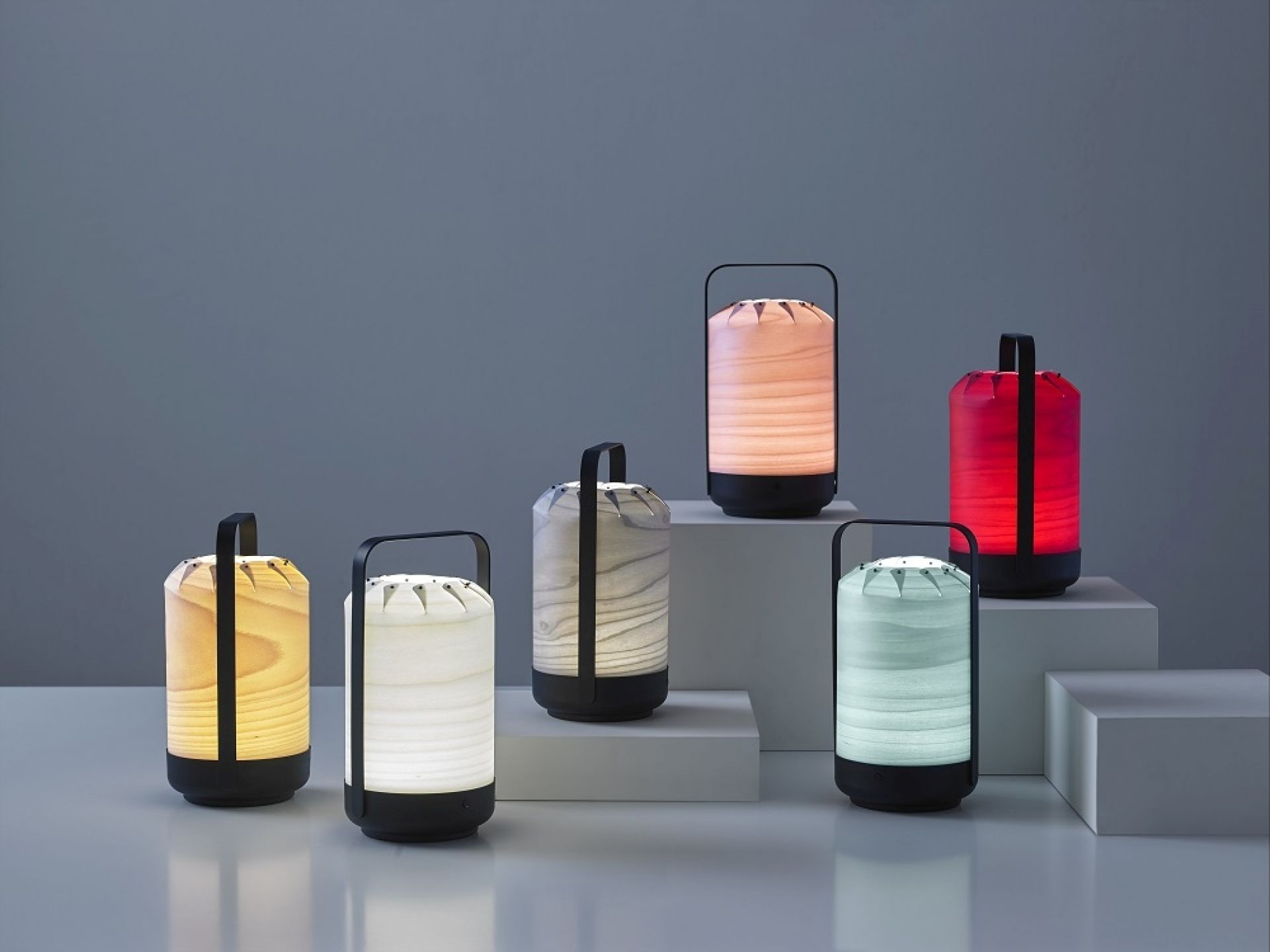 Mehrere Chou Mini LED Akkuleuchten von LZF Lamps in verschiedenen Farben und Holzarten.