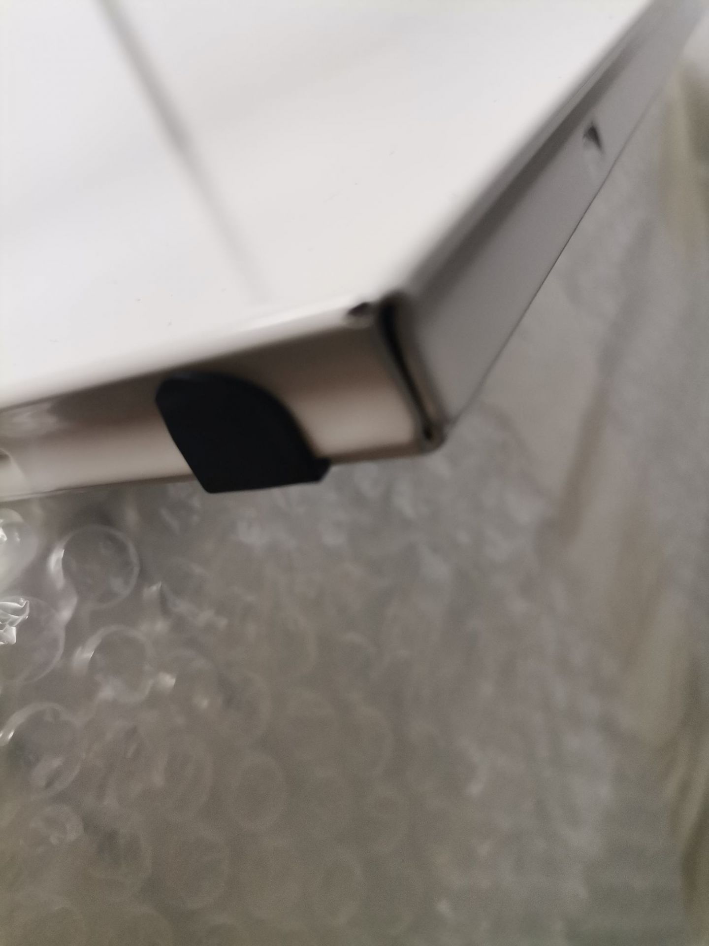 Detailaufnahme eines weißen USM Haller Möbelbauteils mit schwarzem Kantenschutz, Mängelexemplar.
