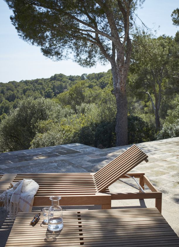 Riviera Sonnenliege von Skagerak by Fritz Hansen im Outdoor-Bereich mit Tisch und Getränken.