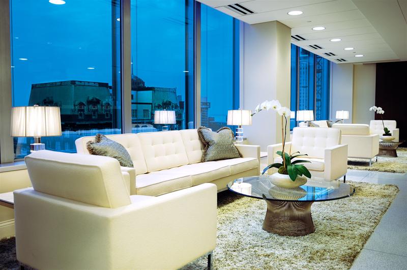 Helles Wohnzimmer mit weißem Florence Knoll Sofa, Sessel und Glas-Couchtisch auf beigem Teppich.