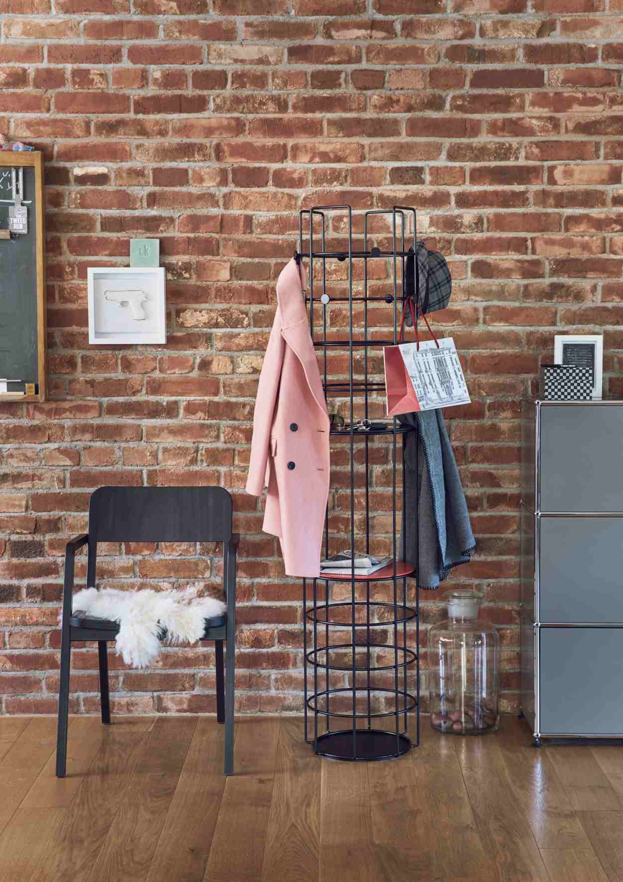 Bazar Garderobe von Richard Lampert, narzissengelb, mit Kleidung vor einer Backsteinwand.