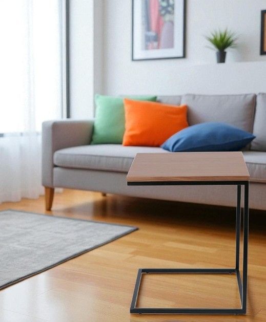 Jan Kurtz Flat Beistelltisch mit Eichenholzplatte und schwarzem Metallgestell neben einem Sofa.