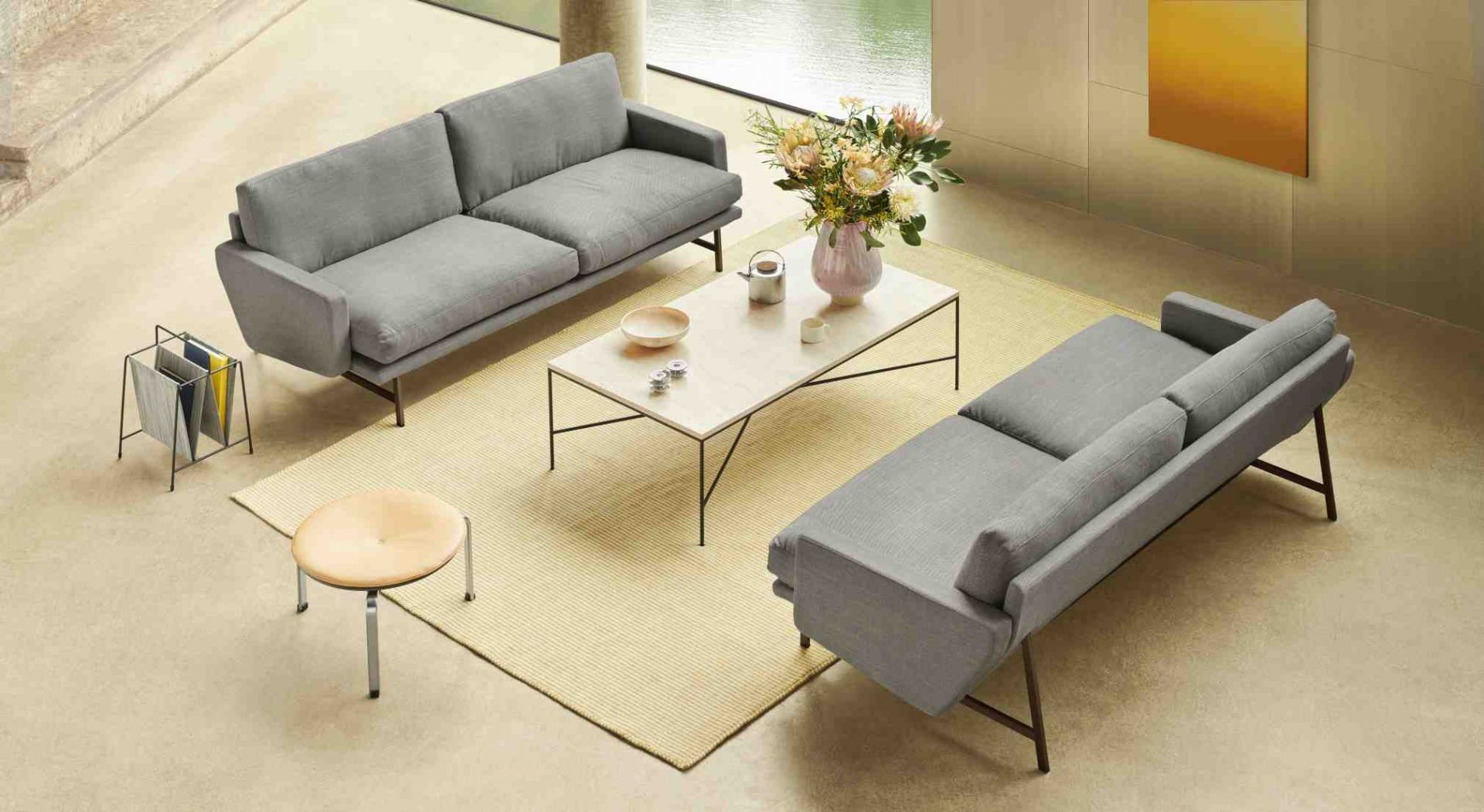 Helle Wohnraum-Szene mit zwei grauen Fritz Hansen Lissoni Sofas, Couchtisch, Teppich und Dekoration.