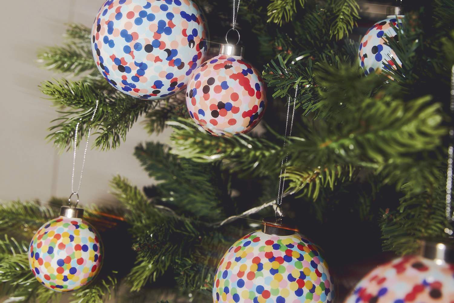 Mehrere bunte Proust Weihnachtskugeln von Alessi am Weihnachtsbaum, festliche Dekoration.