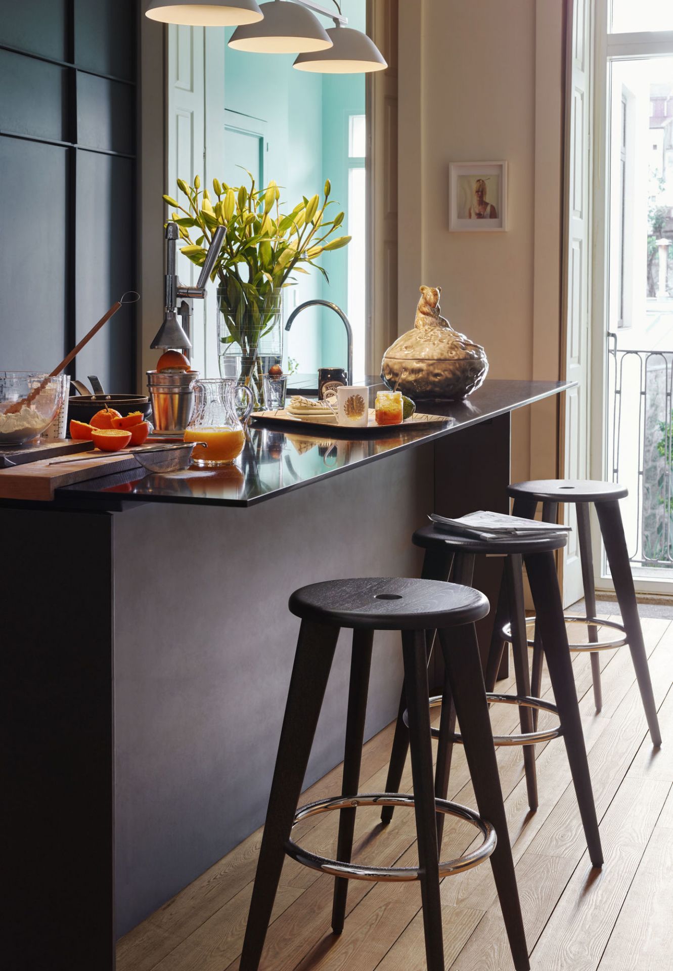 Drei dunkle Barhocker im Vordergrund, Modell Tabouret Haut von Vitra, Eiche natur.