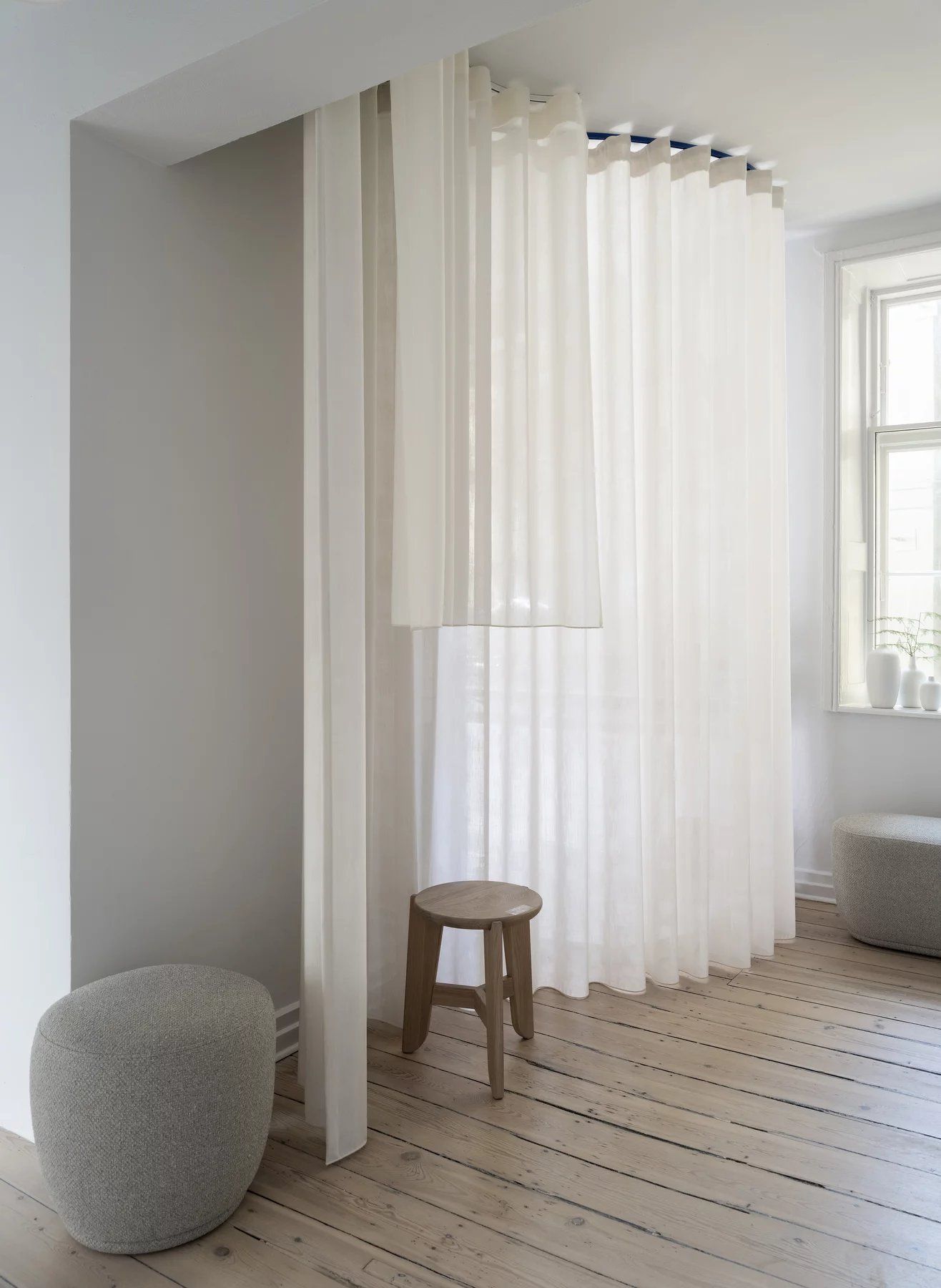 Heller Raum mit Vorhängen, Hocker und Pouf. Dekoration und Möbel für ein gemütliches Zuhause.