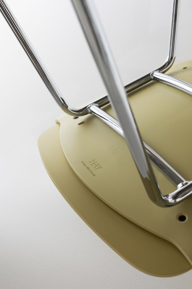 Detailaufnahme der Unterseite eines hellgrünen Hay Armlehnstuhls mit verchromtem Stahlgestell, Fokus auf die Marke.